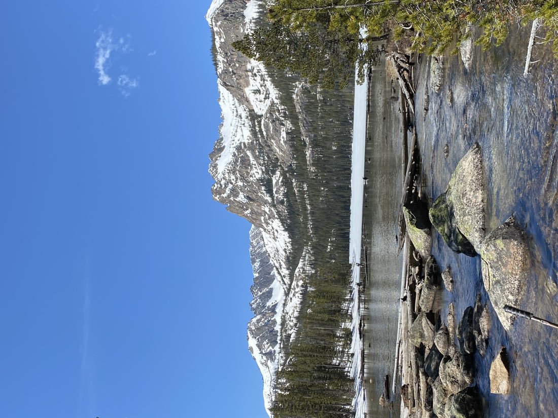 Alpine lake and creek below snowy peaks